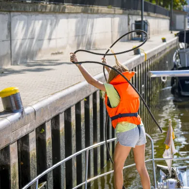 hier wirft ein Mädchen die Leine über den Poller in einer Schleuse