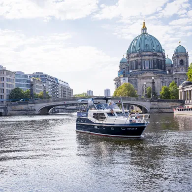 Im Vordergrund ist eine Motoryacht zu sehen, im Hintergrund befindet sich der Berliner Dom